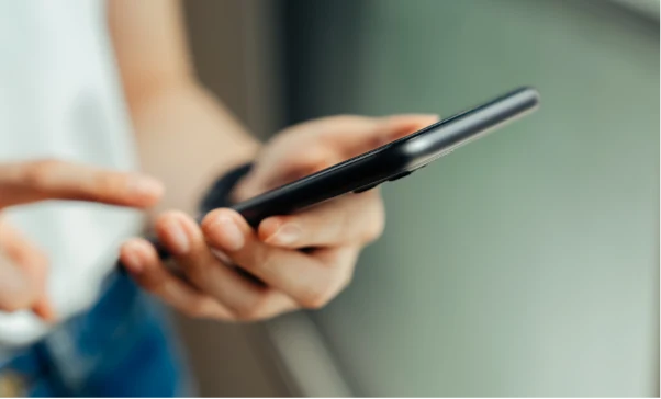 Osoba korzystająca ze smartfona trzymanego w dłoniach